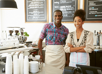 Who Qualifies for a Business Owners Policy? Man and woman small business owners posing in their coffee shop behind the counter