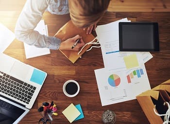 Who is Covered Under My Business Owners Policy? Person working at a desk surrounded by paperwork and a laptop
